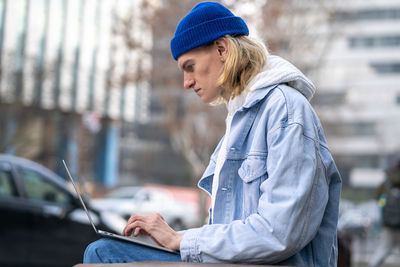 Side view of young woman using mobile phone