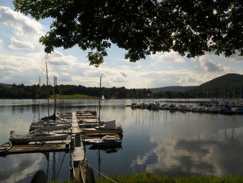 Sailboats moored in lake against sky