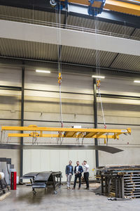 Three men standing on factory shop floor