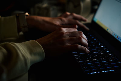 Anonymous woman working on laptop at night