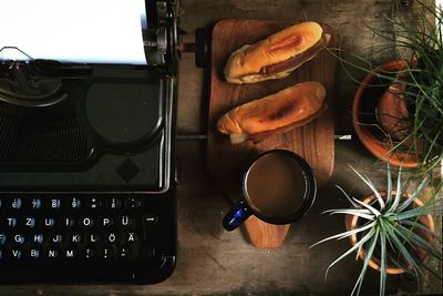 High angle view of food and drink by laptop and potted plants on wooden table