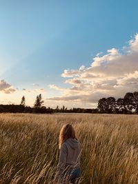 Rear view of woman standing on field against sky