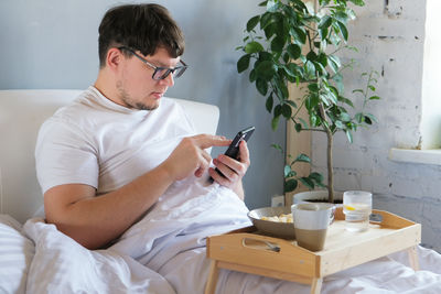 Side view of man using mobile phone while sitting at home