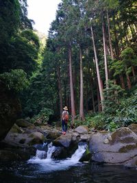 Woman by waterfall in forest