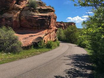 Road amidst rocks and trees against sky