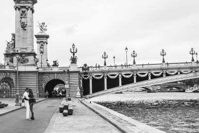 Statue of people at bridge against sky