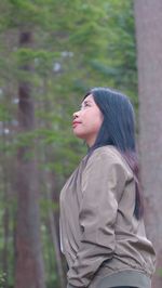 Young woman looking away while standing outdoors