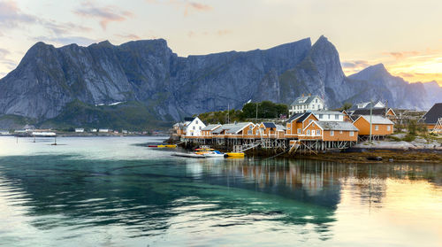 Houses by lake and mountains against sky