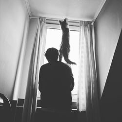 Rear view of man and woman standing against window