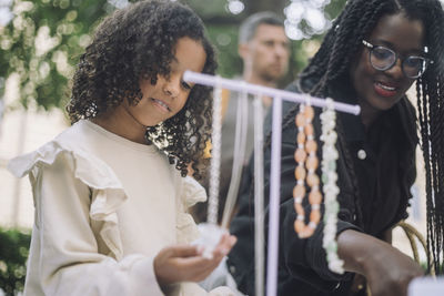 Low angle view of girl buying jewelry with mother while shopping at flea market