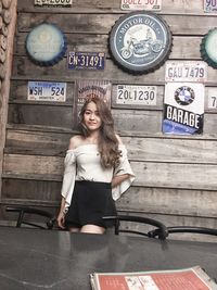 Portrait of smiling young woman standing against wall