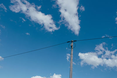 Low angle view of electricity pylon against blue sky