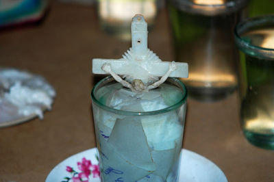 Close-up of glass bottle on table with crucifix