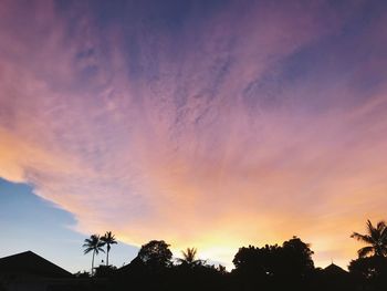 Low angle view of silhouette trees against dramatic sky
