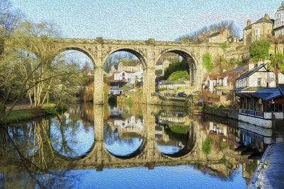 Arch bridge over river against buildings