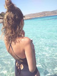 Rear view of woman wearing standing at beach against sky