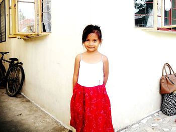 Portrait of young woman standing against red wall