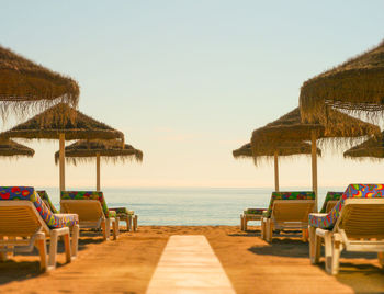 Thatched roofs and lounge chairs at beach resort