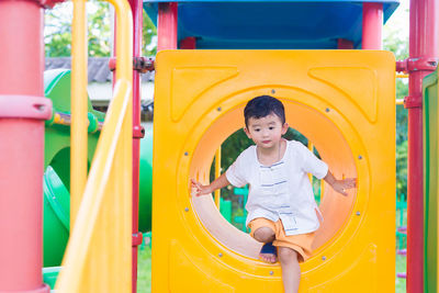 Boy playing on yellow slide in playground