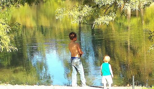 Rear view of father and son in lake