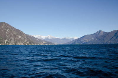 Scenic view of sea and mountains against clear blue sky