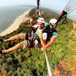 Portrait of men paragliding over landscape