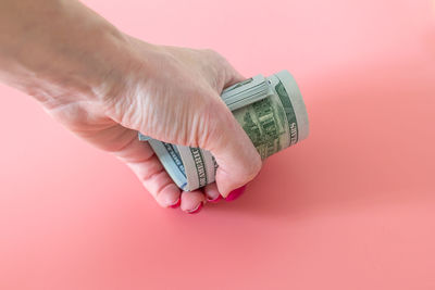 Close-up of hand holding ring over pink background