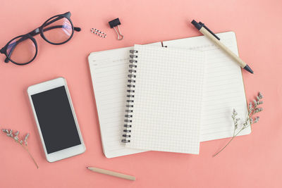 High angle view of books with mobile phone and eyeglasses on table