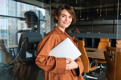 Portrait of young woman standing in city