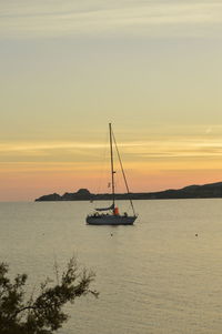 Sailboat sailing on sea against sky during sunset