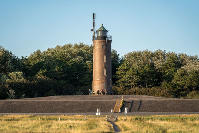 Lighthouse by sea against clear sky