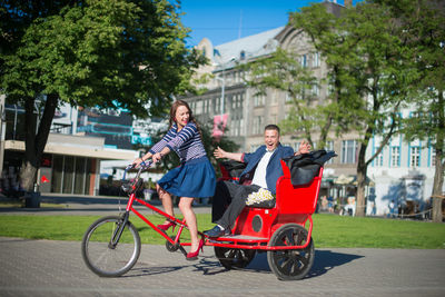 Happy couple traveling in pedicab on street during sunny day