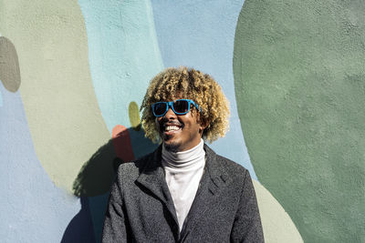 Portrait of smiling young man against wall