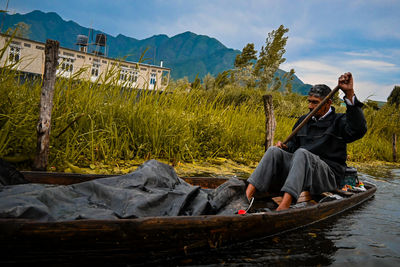 Rear view of man sitting on boat in lake