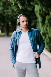 Portrait of young man standing against trees