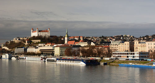 Buildings by river against sky