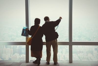 Rear view of man and woman standing in front of window in building