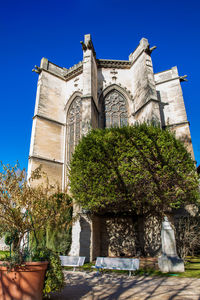 Low angle view of trees and building against sky