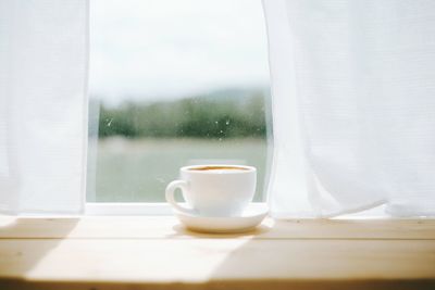 Coffee cup on table against window