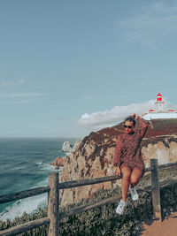 Woman standing by sea against sky