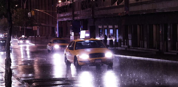 Cars on illuminated city street at night