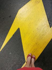 Low section of woman standing on exit sign in parking garage