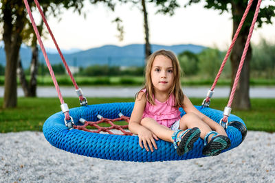 Portrait of girl sitting on swing at playground