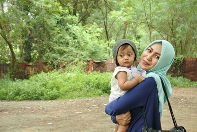 Close-up portrait of woman with daughter standing on field