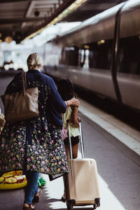 Rear view of women walking on railroad station platform