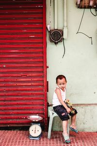 Portrait of young woman sitting on brick wall