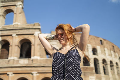 Stylish tourist doing hair near famous monument