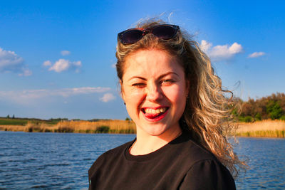 Portrait of smiling young woman in sunglasses against sky
