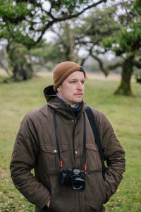 Man wearing hat standing against plants during winter