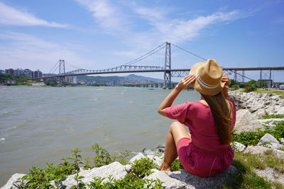 Rear view of woman standing against river